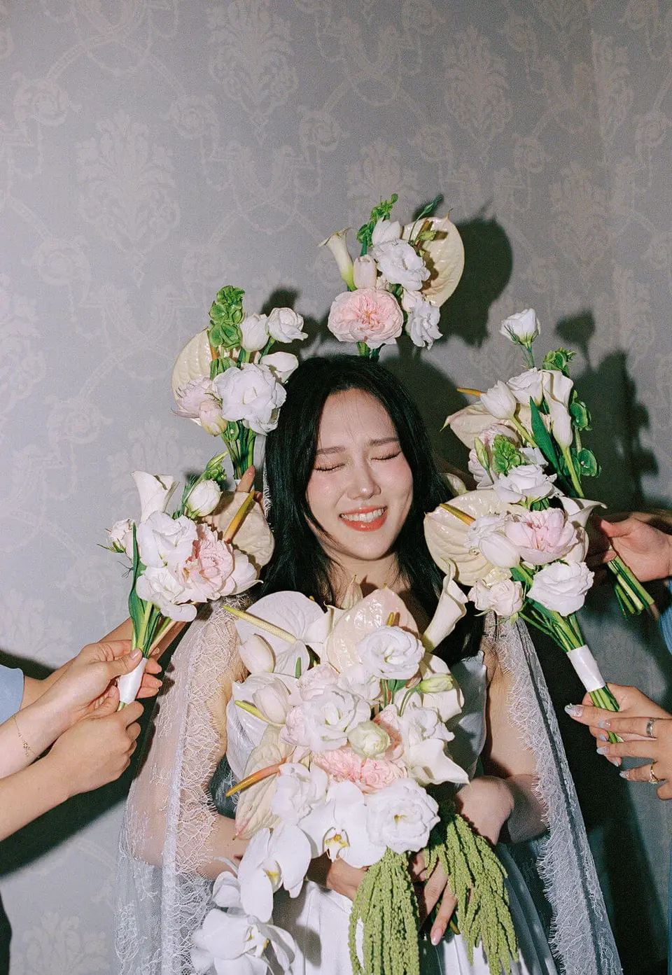 Bridesmaids holding soft white and pale pink bouquets with dusty blue dresses
