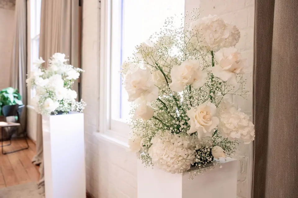Cloud-like white rose, hydrangea and baby’s breath plinth arrangement
