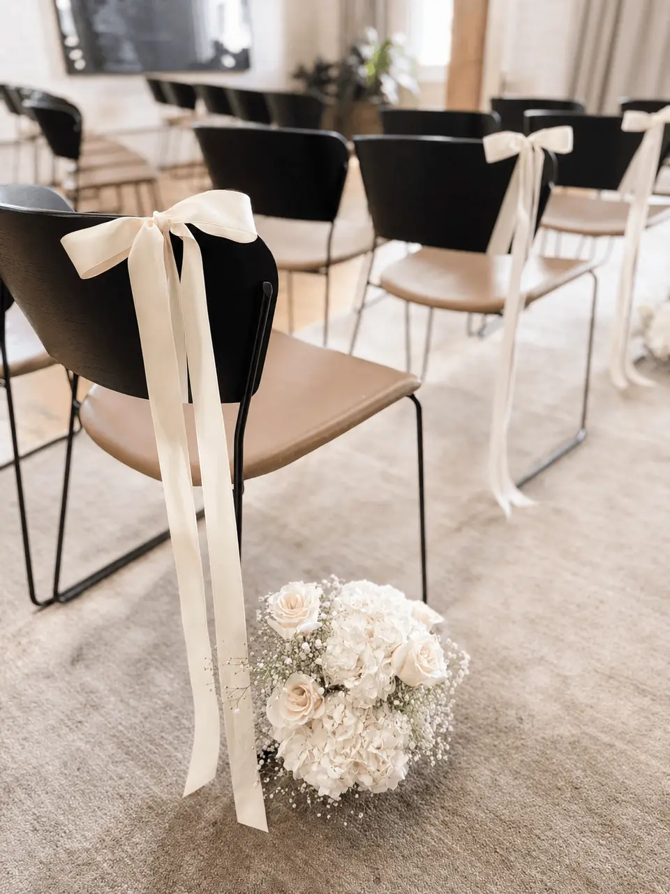 Ivory ribbon chair bows and white flowers decorating the ceremony aisle