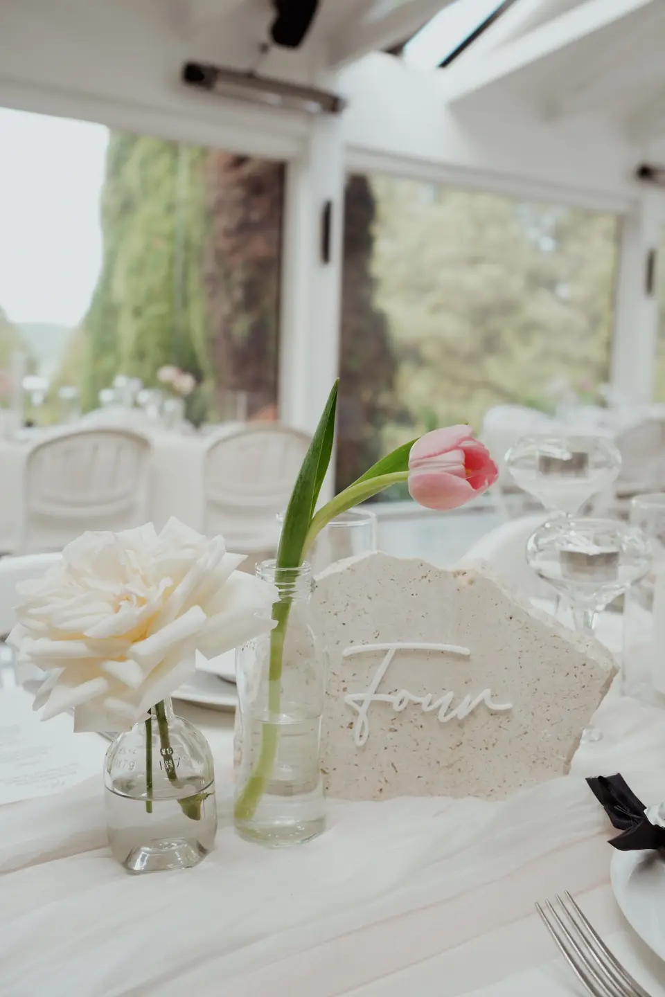 Modern romantic wedding reception styling with bud vases, candles and white linen
