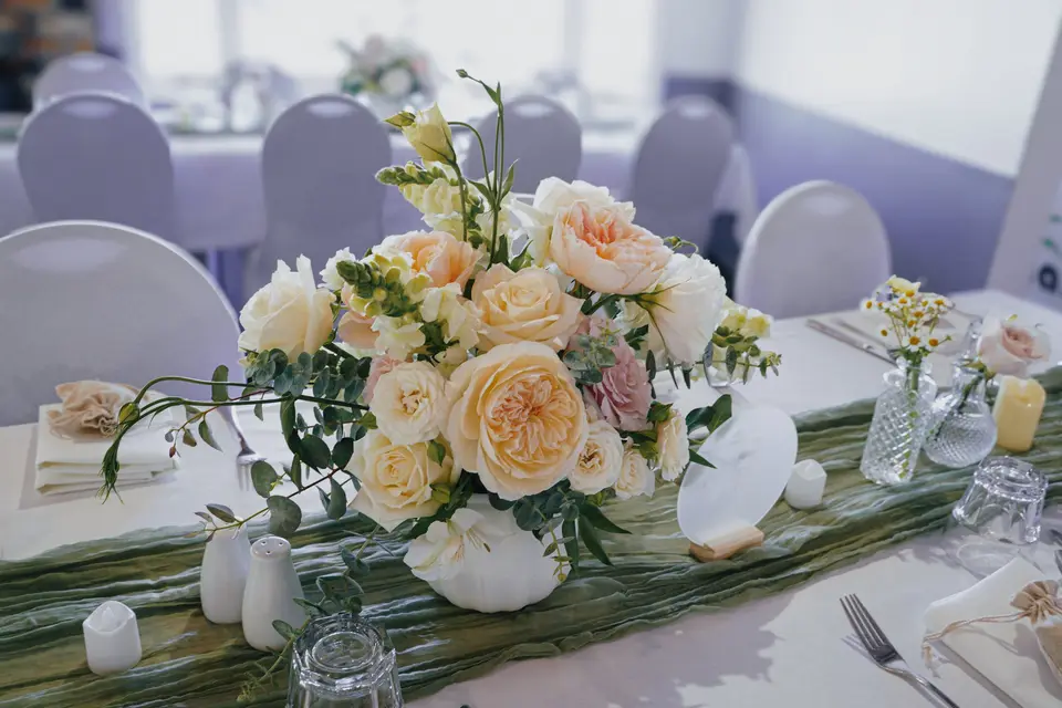 Soft romantic wedding reception styling with central floral arrangements and bud vases by Willow and Peony