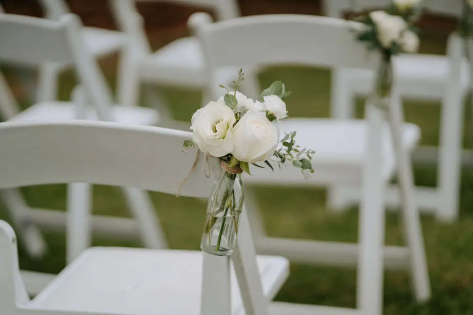 White chair flowers in glass bottles for a wedding aisle